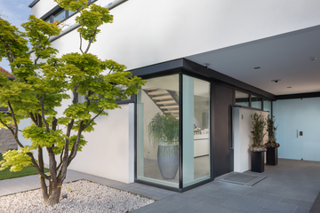 Überdachter Hauseingangsbereich mit einer großzügigen, modernen Hauseingangstür mit seitlichen, raumhohen Glas-Elementen der Firma Maderböck.