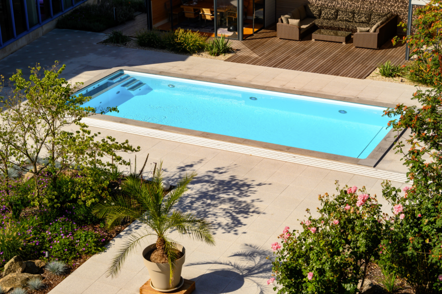 SAUNA-SCHWIMMBAD RUHA Stelzmüller zeigt einen Garten mit großem Swimmingpool und Terrasse.