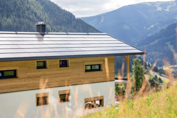 SONNENKRAFT zeigt eine auf dem Dach montierte Photovoltaikanlage eines modernem Hauses in den Bergen.