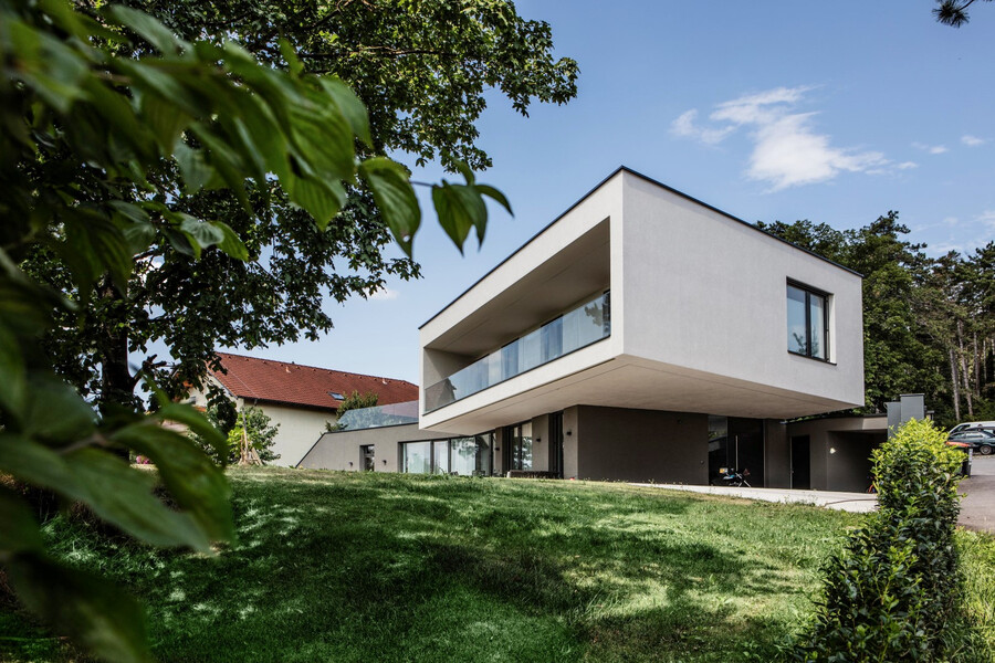 Modernes Architektenhaus mit schönem Garten, großer Terrasse, großzügigem überdachtem Balkon mit Verglasung und einer weißen Fassade von Baumit.
