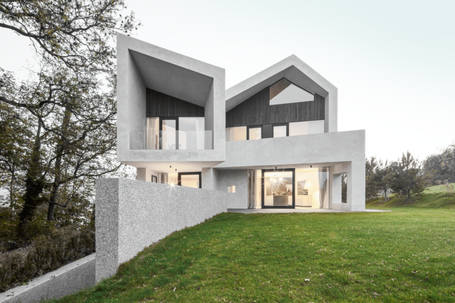 Betonmarketing Österreich zeigt ein formschönes Haus mit Betonfassade, Schrägdach, großer Fensterfront und Garten.