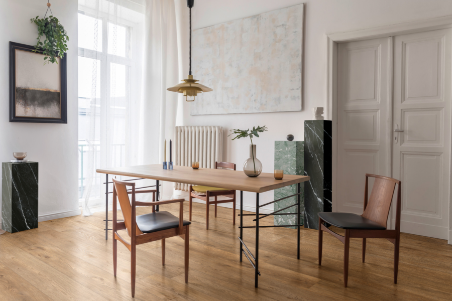 Felbermair zeigt ein minimalistisches Esszimmer mit einem Holztisch und Stühlen aus Leder und Holz und dekorativen Elementen in Marmoroptik und verschiedenen Grüntönen von Ragno.