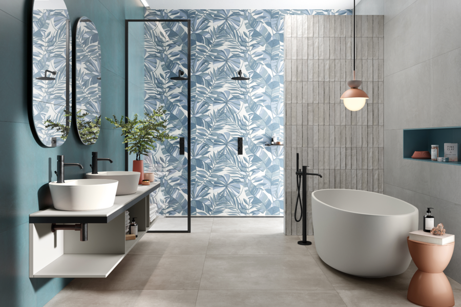 Fliesendorf zeigt ein Badezimmer mit weißen Doppelwaschbecken, zwei ovalen Spiegeln an der Wand, Dusche mit blau gemusterter Wand.