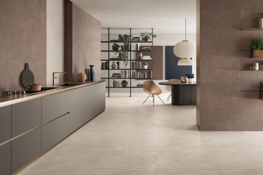 Fliesendorf zeigt eine offene Küche mit einem grauen Küchenblock und goldenen Akzenten mit Blick ins Esszimmer und beigem Fliesenboden.