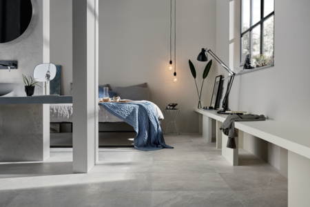 Fliesendorf präsentiert die hell marmorierten Fliesen am Boden eines Schlafzimmers mit Doppelbett inklusive Badezimmer.