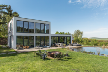 Modernes Einfamilienhaus mit schönem Garten mit Schwimmteich, Feuerschale und bodentiefen Holz-Alu-Fenstern und Hebeschiebetüren der Fusionline von Gaulhofer.