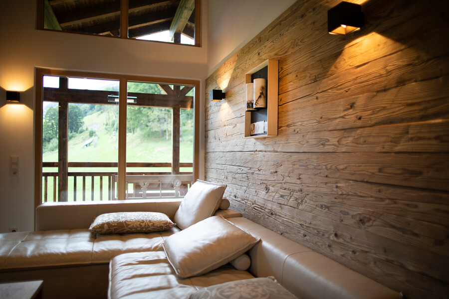 Wohnbereich mit gemütlicher Ledercouch und großem Fenster von Gaulhofer mit eleganter Oberfläche.