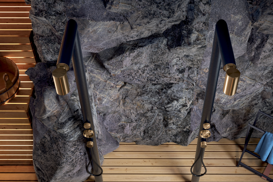 GESSI zeigt zwei Brausen in schwarz mit goldenen Akzenten in der Nahaufnahme vor einer Steinwand und Holzboden.