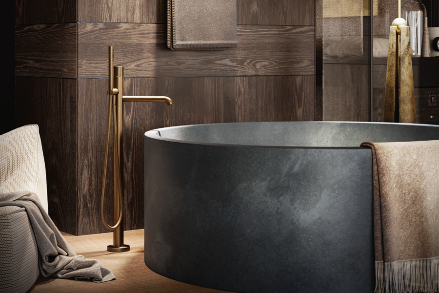 GESSI zeigt die freistehende Badewanne aus dunklem Stein mit Armatur vom Boden aus in Bronze.