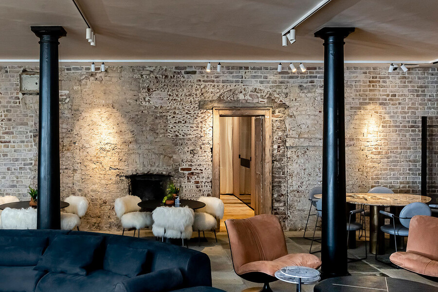 Aufenthaltsraum in der Casa GESSI London mit bequemen Sofas, Kaffeetischen, schwarzen Säulen sowie einem Besprechungsraum.