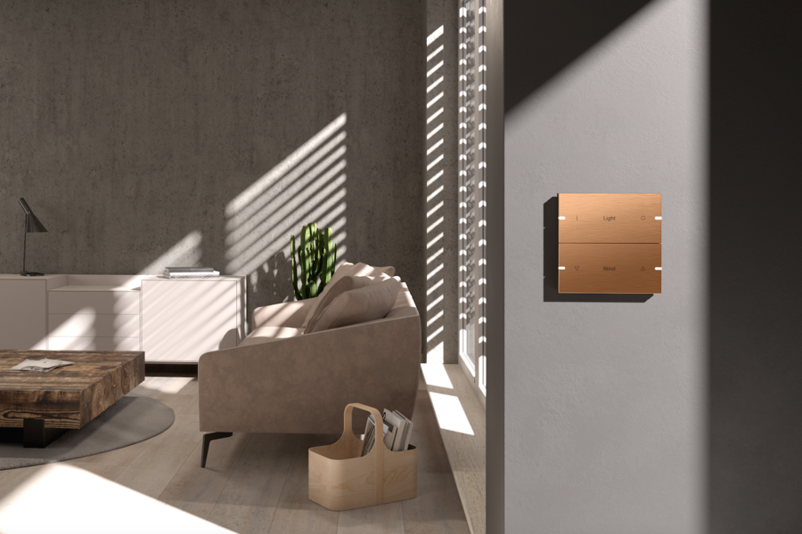 Gira zeit einen bronzefarbenen Touchschalter für ein Wohnzimmer mit einer Couch in Naturtönen, Holzboden und einem runden, freiliegenden Teppich mit Beistelltisch.