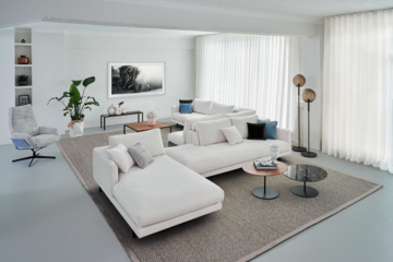 Wohnraum mit ausladender Couchlandschaft und runden und eckigen Beistelltischen von Bielefelder Werkstätten präsentiert von Grill & Ronacher.