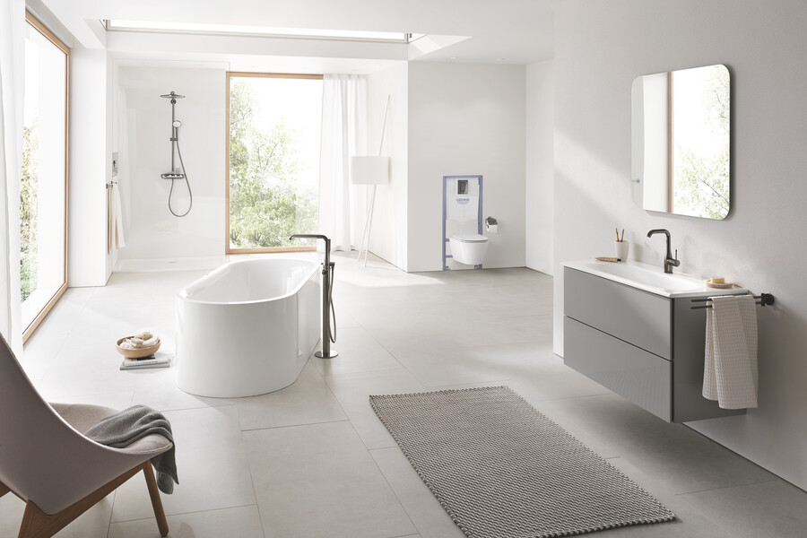 GROHE zeigt ein helles Badezimmer mit freiliegendem Teppich, freistehender Badewanne, WC, Dusche und großem Waschtisch mit Designer-Unterschrank von den Möbelherstellern BURGBAD.