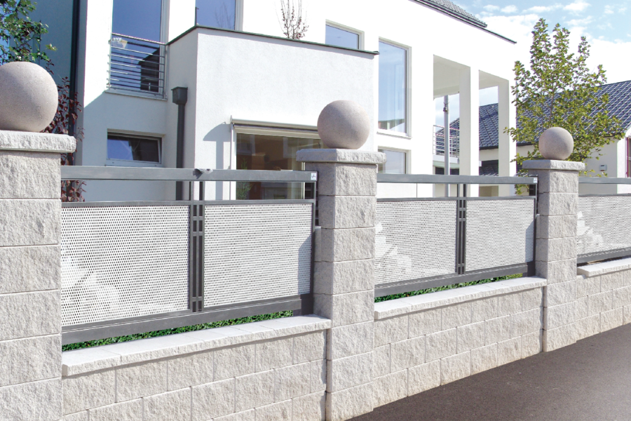 Modernes Architektenhaus mit einem Zaun bestehend aus hellgrauen Elementen und einer Steinmauer mit Säulen-Elementen von Häusler.
