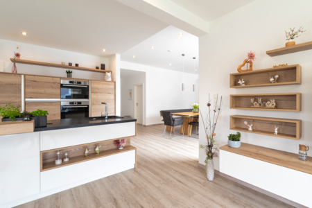 Hartl Haus zeigt eine Wohnküche aus Holz mit weißen Elementen, Boardregalen an der Wand und Osterdeko darin.