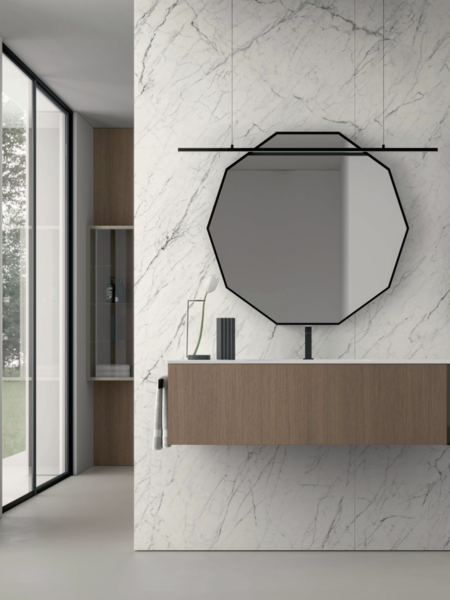 IDEA GROUP zeigt ein minimalistisch, modernes Badezimmer mit Waschtisch an der Wand mit weißen Marmorfliesen, zehn-eckigem Spiegel und Hängeschrank.