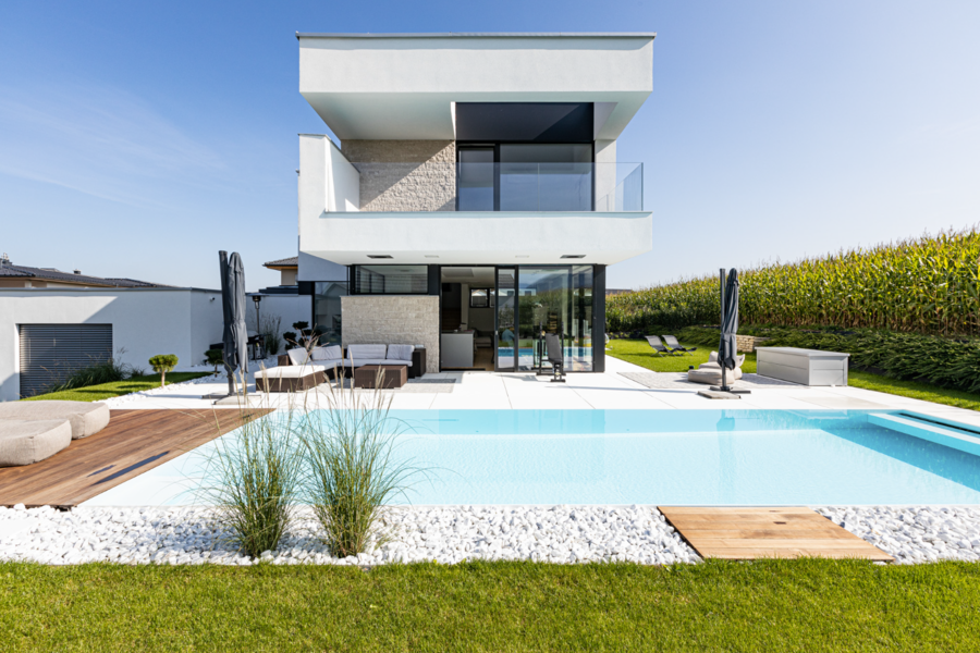 Innovativer Poolbau Ritzberger zeigt ein Architektenhaus mit großer Terrasse und Pool.