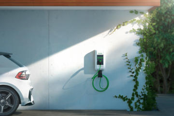 KEBA zeigt eine Ladestation für E-Autos an der Wand einer weissen Garage mit Pflanzen.