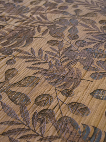 Keplinger zeigt eine Holzgravur in der Nahaufnahme mit schönem Muster bestehend aus Blättern in verschiedenen Größen und Formen.