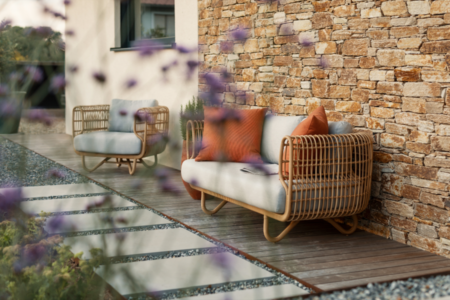 Stilvoll angelegte Terrasse mit unterschiedlichen Naturmaterialien und stylischen aber dennoch gemütlichen Gartenmöbeln, erhältlich bei Nentwich Gartenbau.