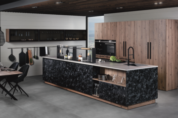 Pointinger | wohnen zeigt eine ewe Küche aus schwarz-weißen Marmorfronten, Holzkästen und einem Esstisch mit Stühlen im gleichen Design.