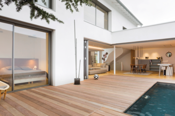 SOLARLUX präsentiert das übers Eck gehende Glasfaltfenster eines Einfamilienhauses mit Pool, Holzverbau rundherum und Zugang zur Küche und Wohnbereich.