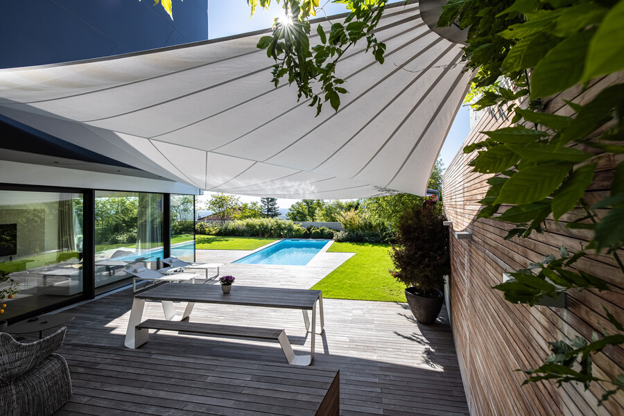 Moderne Holzterrasse mit schattenspendendem Sonnensegel von SunSquare und elegantem Sitzbereich.