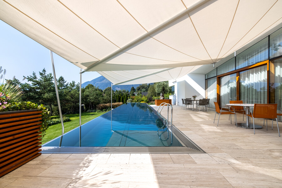 Große Terrasse mit elegantem Edelstahlpool, beschattet mit zwei großen, modernen Sonnensegeln von SunSquare.