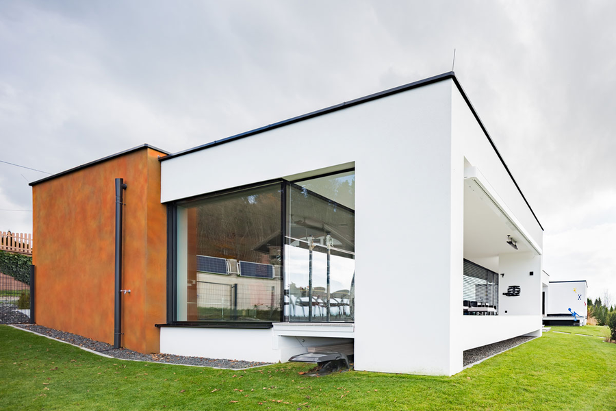 Modernes Haus im Bauhaus-Stil mit überdachter Terrasse, Flachdach und teilweiser Außenfassade in Rostoptik, gestaltet mit Synthesa Fassadenprodukten.