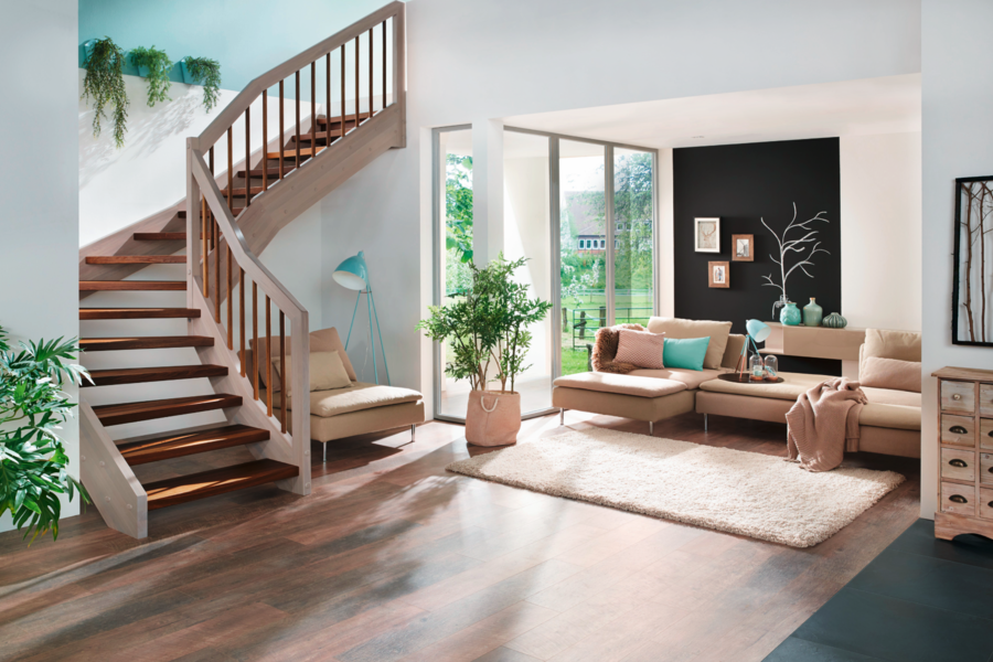 Formschöne Holz-Ecktreppe von Treppenmeister in einem offenen Wohnzimmer mit gemütlichem Sofa.