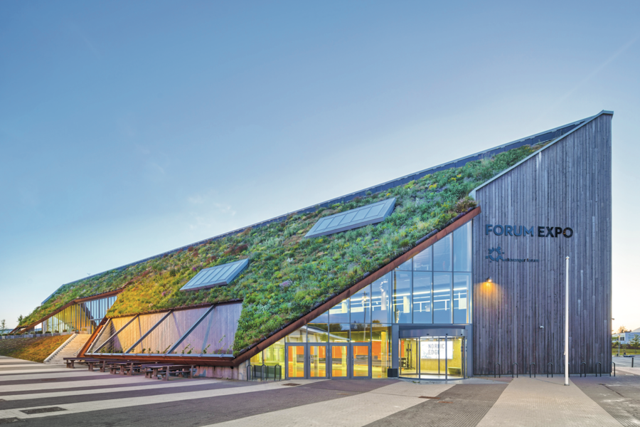 ZinCo zeigt eine moderne Messehalle mit schrägem Dach und Dachbegrünung.