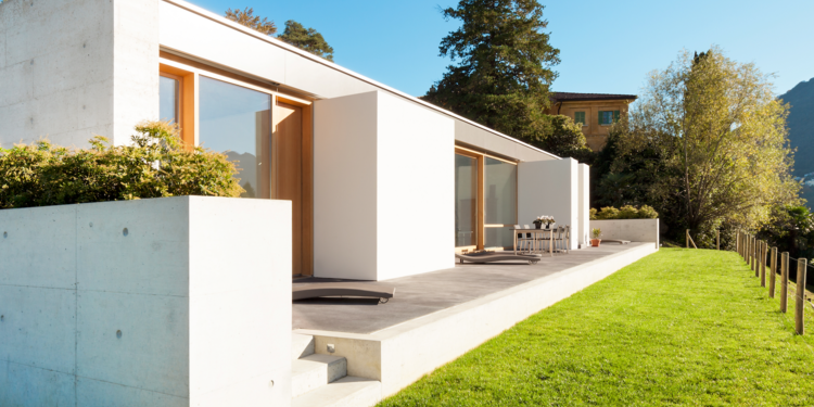 Modernes Betonhaus mimt Flachdach und Ganzglassysteme mit Holzrahmen und Terrasse mit Blick auf das Tal.