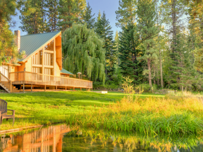 Holzblockhaus mit grünem Metalldach auf großem Grundstück in naturbelassender Landschaft.
