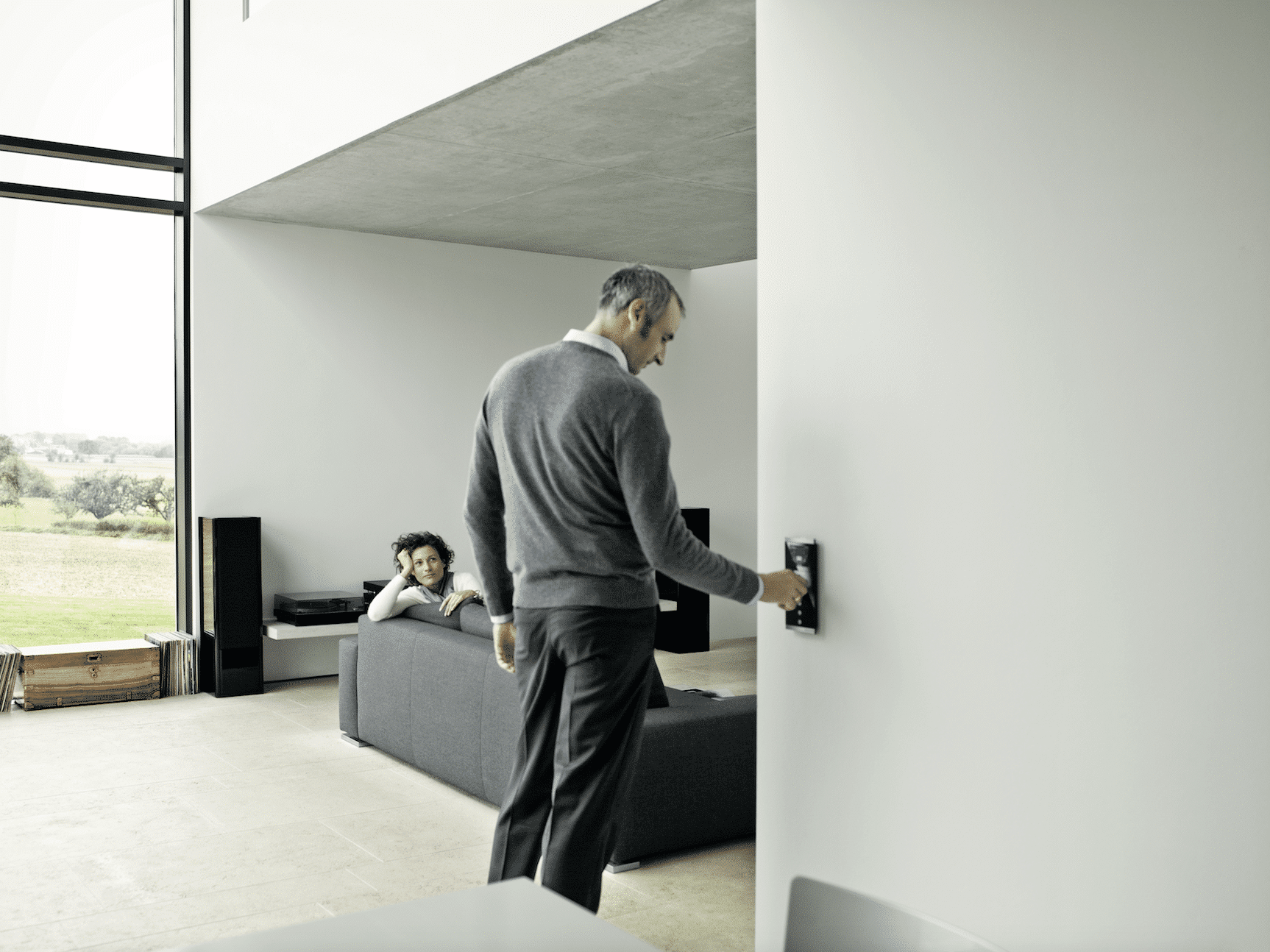 Mann bedient Schalter von ABB Busch-Jaeger, der an einer Wand neben dem Wohnzimmer angebracht ist.