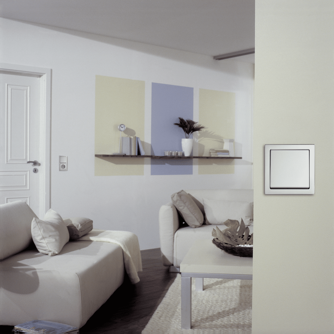 Lichtschalter von ABB Busch-Jaeger, der an einer Wand neben einem hellen Wohnzimmer angebracht ist.