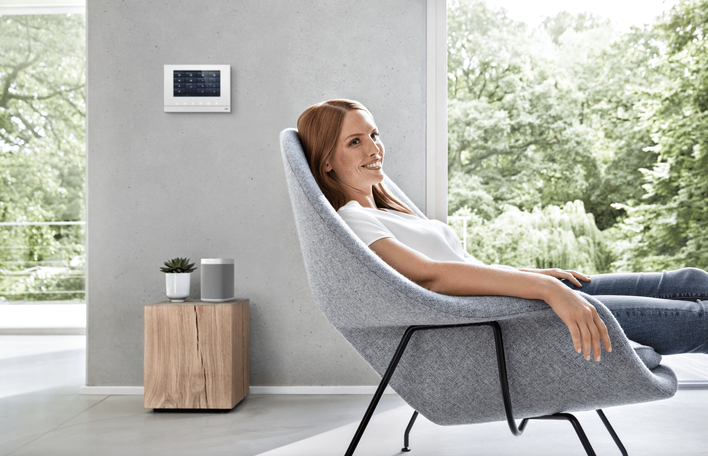 Frau sitzt gemütlich im Sessel und genießt Smart Home von ABB Busch-Jaeger.