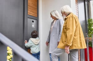 ABB zeigt eine Busch-Jaeger Türkommunikationseinheit mit Tasten und Kamera in Edelstahl bei einem Hauseingang.