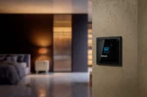 ABB zeigt einen Busch-Jaeger Regler für Jalousie in schwarz in einem Schlafzimmer.