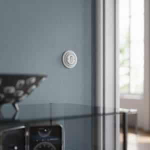 ABB zeigt einen Busch-Jaeger Schalter im Retrodesign in studioweiß an einer graublauen Wand.