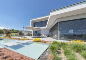 Ein modernes Haus mit Flachdach, Garten, Pool und großzügiger gefliester Terrasse von AL Architekt ZT GmbH.