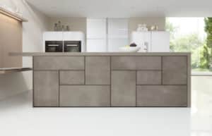 Ein griffloses, geometrisches Frontendesign an einer Kochinsel in beiger Betonoptik mit wandmontierter schwebender Sitzbank aus Holz von ALPHAOMEGA.