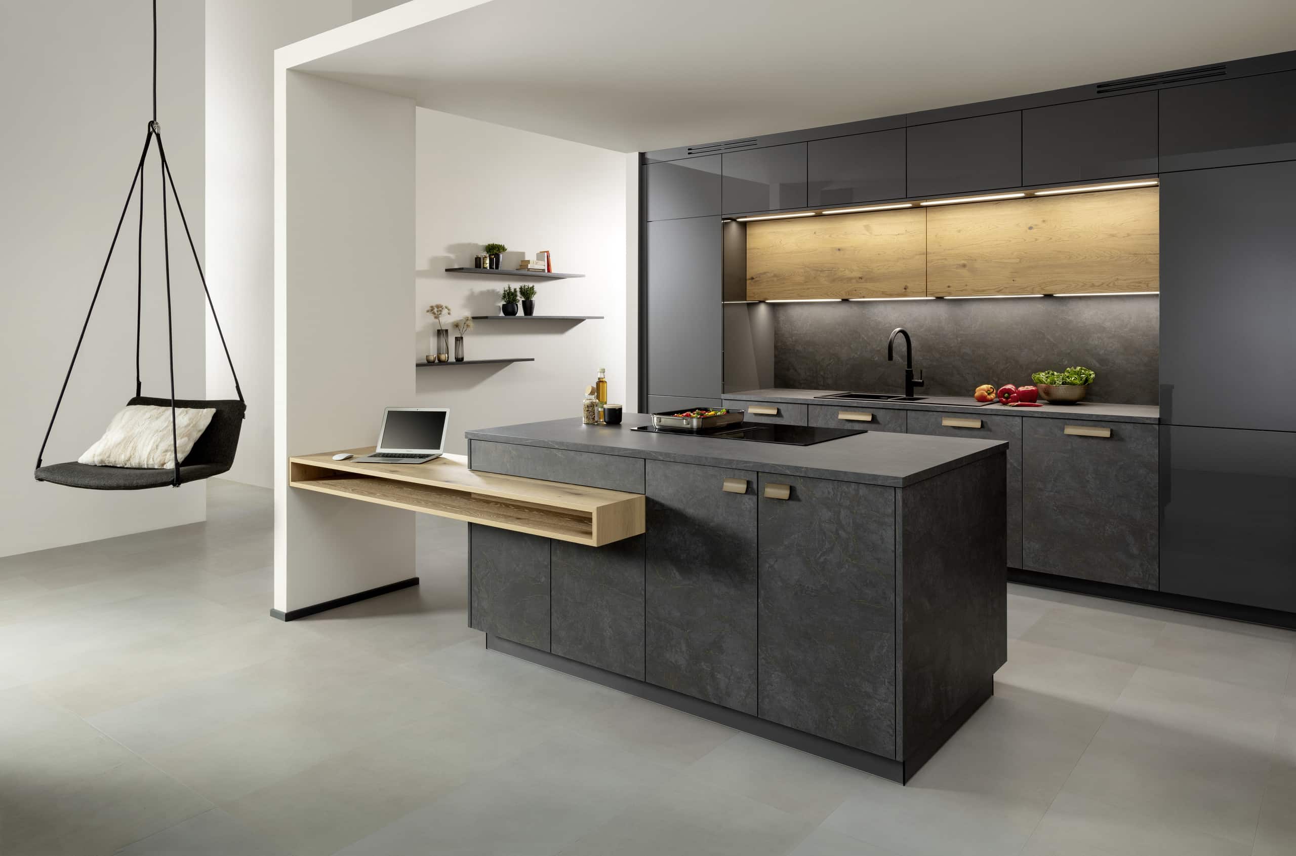 Eine Küche mit Küchenzeile und Kochinsel in Anthrazit mit Patina, einer angestückelten Theke aus Holz und einem gemütlichen Hängesessel von ALPHAOMEGA.