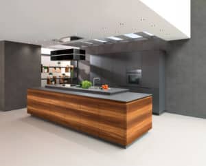 Eine grifflose Kücheninsel mit Holzfronten, Niro­stahl-Arbeitsplatte, schwebender Dunstabzugshaube und Spotbeleuchtung von ALPHAOMEGA.