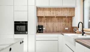 Moderne DAN Küche mit grifflosen Fronten in polarweiss, Holzdetails und Kochinsel mit Marmorarbeitsplatte gezeigt von Salzburger Bad & Wohnraum.