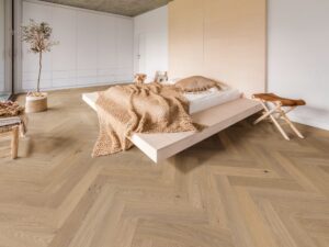 Ein helles Schlafzimmer mit Fischgrät-Eichenparkett und natürlichem Ambiente von WOODBASE gezeigt von Salzburger Bad & Wohnraum.