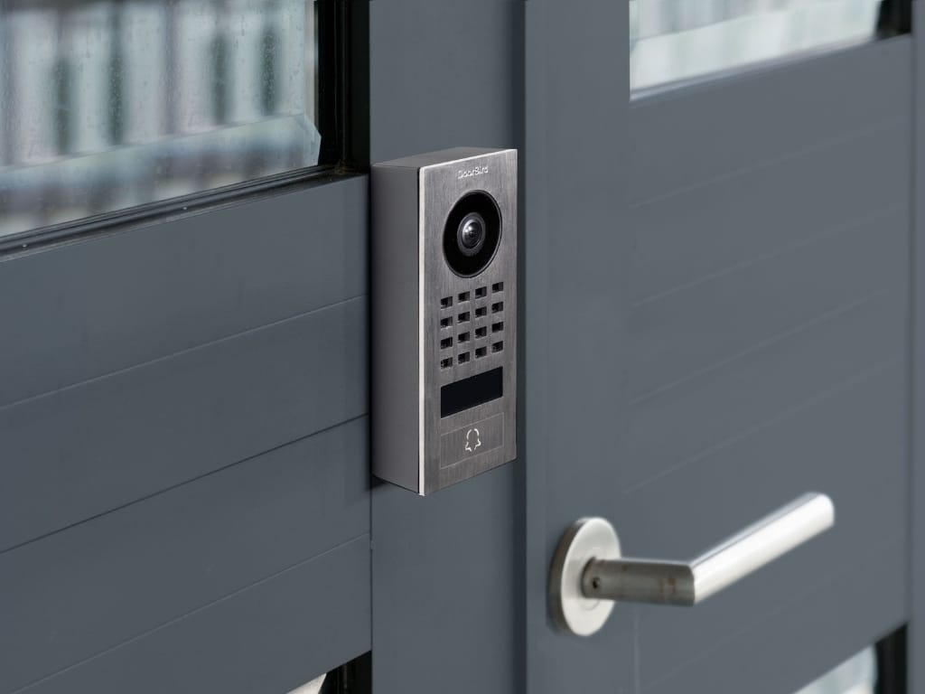 Bird Home Automation zeigt eine Aufputz Türsprechanlage mit Glockentaste, Kamera und Lautsprecher aus gebürstetem Edelstahl.