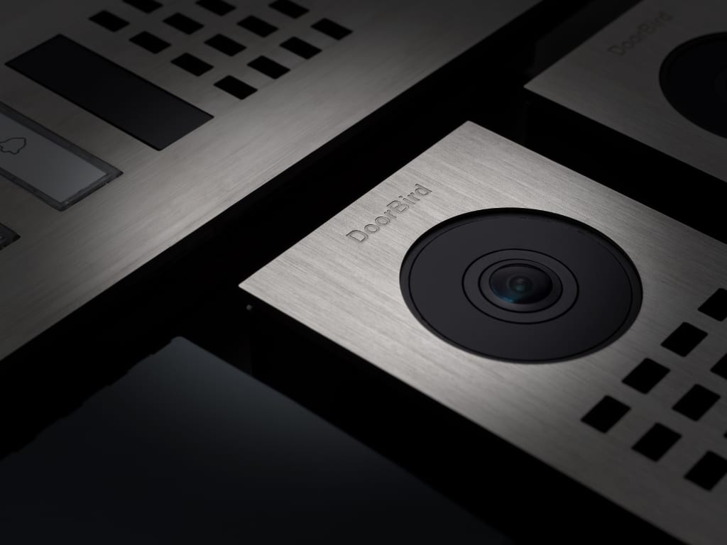 Bird Home Automation zeigt eine Detailaufnahme einer Türsprechanlage mit Kamera und Lautsprecher aus gebürstetem Edelstahl.