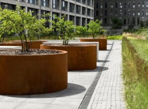 Ein moderner, runder Pflanzkübel aus Cortenstahl von Blumentrog-Flexi steht im Außenbereich und überzeugt durch seine markante Rostoptik sowie ein zeitlos elegantes Design (Montage).
