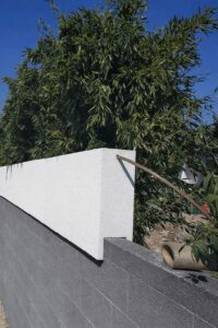 Ein moderner Pflanzkübel auf einer Sichtschutz- bzw. Grundstückswand - eine Sonderlösung in einer Nut-und-Feder-Ausführung von Blumentrog-Flexi.