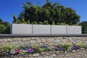 Vier moderne hellgraue Pflanzkübel auf einer Sichtschutz- bzw. Grundstückswand von Blumentrog-Flexi.